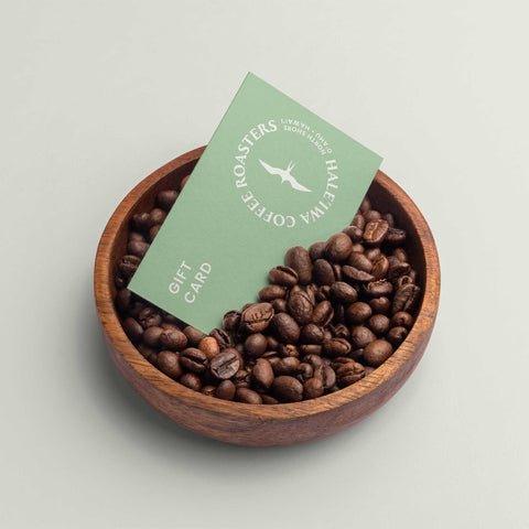 Haleiwa Coffee Roasters Gift Card in a wooden bowl of fresh roasted Hawaiian coffee beans